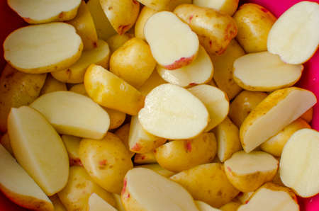 Raw chopped potatoes in a plastic bowl.の写真素材