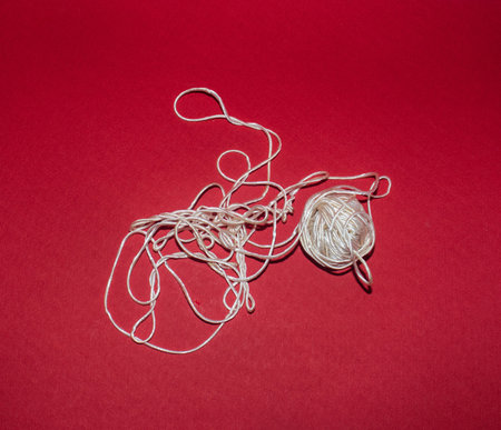 Ball of white thread on red background. Top view. Flat lay.