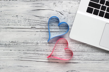 Background of a valentine on a wooden table with a laptop and hearts. Valentines Day greeting card....