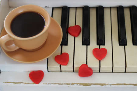 Red hearts and a cup of coffee are decorated with piano keys. Valentine's Day .の写真素材