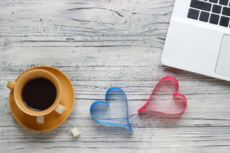 Background of a valentine on a wooden table with a laptop cup of coffee hearts beside a napkin for writing. Valentine's Day.の写真素材