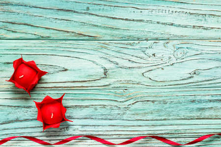 Two candles of red color on a background of turquoise wood. The concept of Valentine's Day.の写真素材