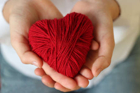Children's hands hold a heart of red thread for knitting. Valentine's Day .の写真素材