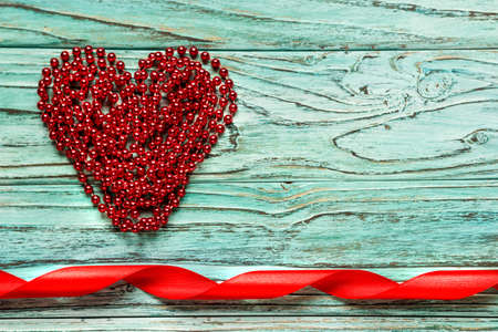 Red heart piled of beads on a wooden turquoise background. The concept of Valentine's Day.の写真素材