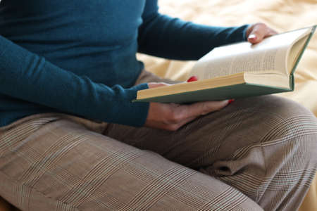 beautiful girl is reading a book in the bedroom, on the bed. concept of home and comfort.の写真素材
