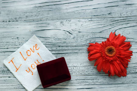 On a wooden background there is a flower in the form of a heart next to a note with wishes for Valentine's Day. The concept of Valentine's Day.の写真素材