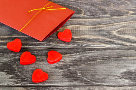 On a dark wooden background there are hearts with a gift envelope. Valentine's day concept.