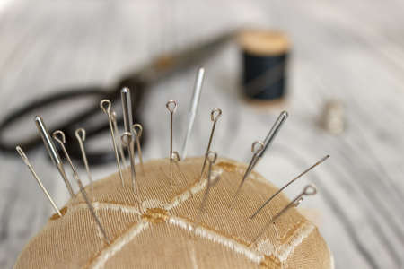 On a white wooden background is a spool of thread with a needle scissors and a place for text.の写真素材