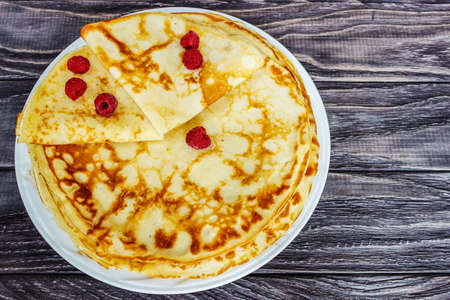 Pancakes on a white plate with honey and a cup of milk. Tasty breakfast.Homemade pancakes with raspberries, close-upの写真素材