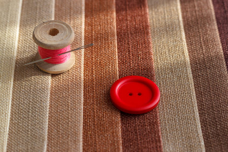 Multicolored fabric samples. A button with a needle and a thread on the tissues with space for text.