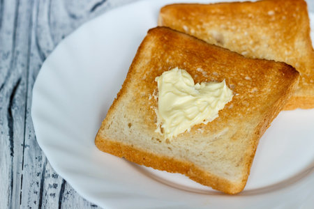 Still life with bread and butter in a white plate on a wooden backgroundの写真素材