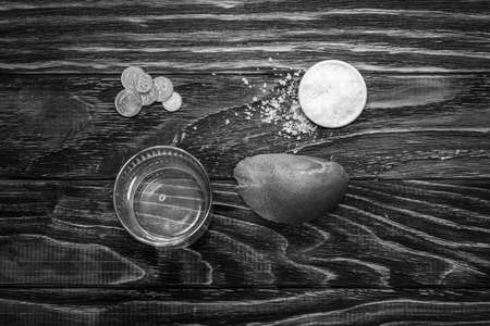 A glass of water and a piece of bread on the table in front of the folded wrinkled hands of a retired old man. Poverty and the problems of retirees of social security.の写真素材