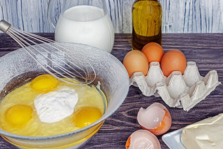 Ingredients for pancakes: milk, eggs, sugar, salt, flour, vegetable oil on a wooden white...