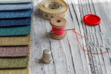 Multicolored fabric samples. A button with a needle and a thread on the tissues with space for text.