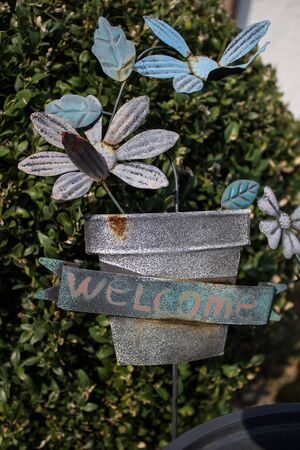 loseup of green basket with fresh flowers and welcome sign text written in black on wall near doorの写真素材