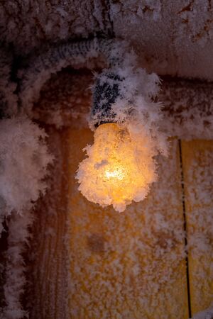 Snow crystals on a wooden wall and a light bulb.の写真素材