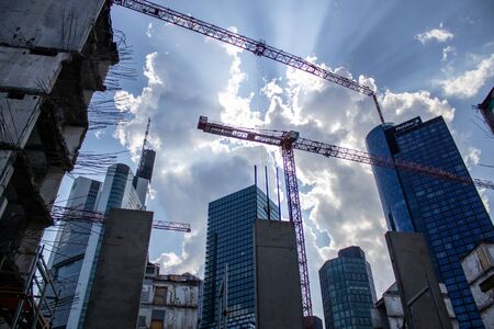 Construction of high-rise buildings in the city. Construction site next to a modern office and residential building. The crane works. Industrial background.の写真素材