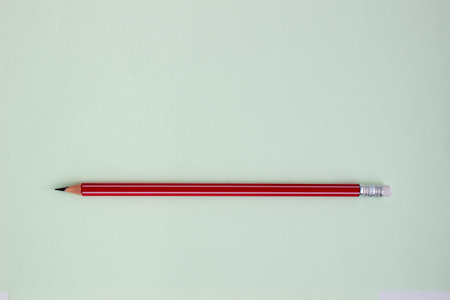 One red pencil on a light green background.