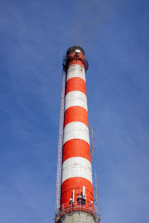 Red and white brick industrial pipe against the blue sky.