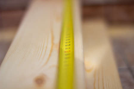 A man measures wooden boards with a tape measure and makes marks with a pencil.の写真素材