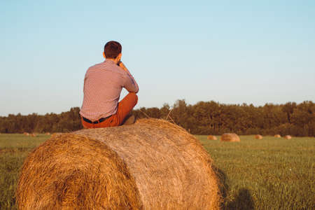 a Young boy sits on a hay bale and enjoys living happy on the country.の写真素材