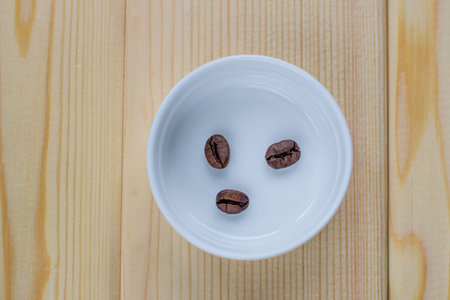 A few coffee beans in a white Cup on a wooden background