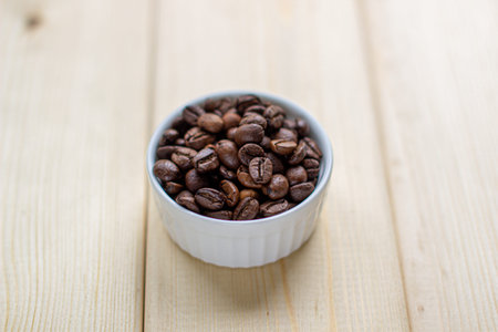 White mug with Cup of coffee beans on wooden background with selective focus and crop fragment.