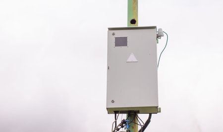 White electric box on a pole outside the house. Industrial, urban electric box
