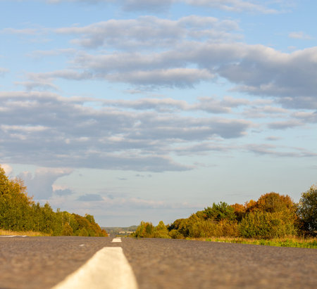 A long white stripe, like a road marker. A road into the distance between fields and forests. High...