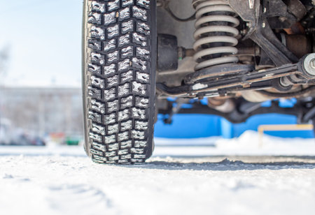 Car wheel on snow in winter close-up. The suspension and chassis of the car are visible. The car is...