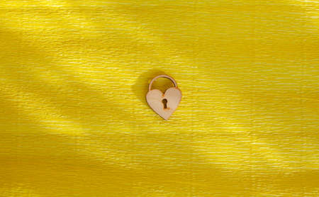A wooden heart with a keyhole on a yellow background. There is a place for the text.の写真素材