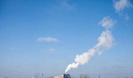 White thick smoke from the boiler room chimney. Smoke against the blue sky. Air pollution. Heating...