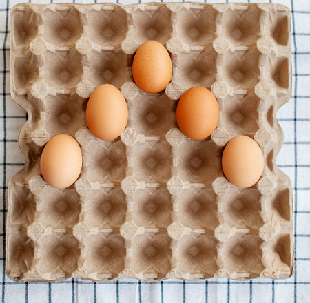 A few brown eggs among the empty cells of a large cardboard bag, a chicken egg as a valuable...