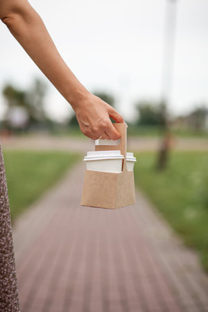 White paper cup with coffee in woman hand. Time for drink coffee in city. Coffee to go. Enjoy moment, take a break. Disposable paper cup closeup. Delicious hot beverage. Blank space for text, mockupの写真素材