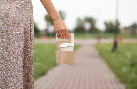 White paper cup with coffee in woman hand. Time for drink coffee in city. Coffee to go. Enjoy...
