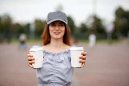 Two white paper cup with coffee in woman hand. Time for drink coffee in city. Coffee to go. Enjoy moment, take a break. Disposable paper cup closeup. Delicious hot beverage. Blank space for text,の写真素材