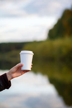 White paper cup with coffee in woman hand. Time for drink coffee in city. Coffee to go. Enjoy moment, take a break. Disposable paper cup closeup. Delicious hot beverage. Blank space for text, mockupの写真素材