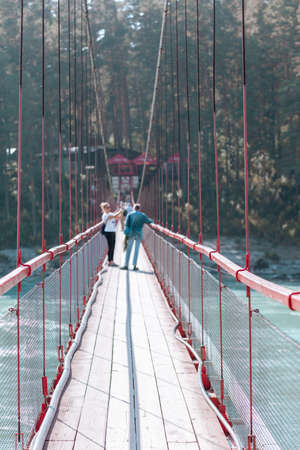 A suspension bridge over a wide river in the mountains. Safe crossing of the bridge from one bank to the other.の写真素材