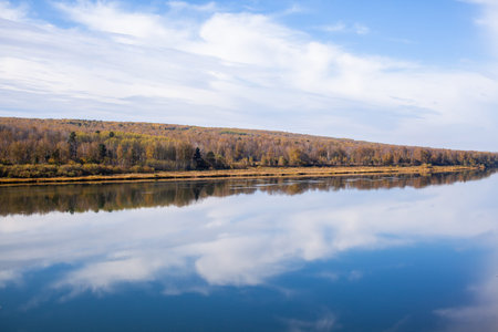 Beautiful, wide river autumn among the woods. Calm and quiet place with autumn colors. In the middle...