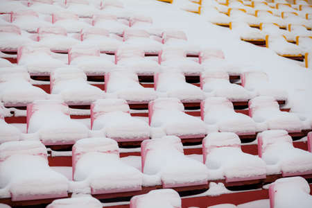 Plastic seats in a row at the stadium are covered with snow snow.の写真素材