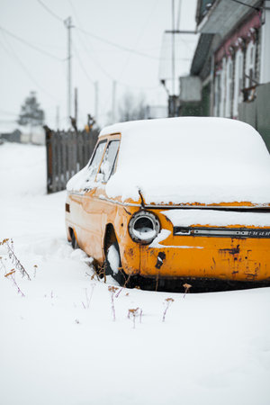 Old yellow wrecked car in vintage style. Abandoned rusty yellow car. of the headlights of the front view of a rusty, broken, abandoned car near the house. Russia, Kemerovo Region, November 25, 2021のeditorial素材