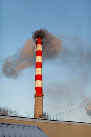 White thick smoke from the boiler room chimney. Smoke against the blue sky. Air pollution. Heating of the city. Industrial zone.の写真素材