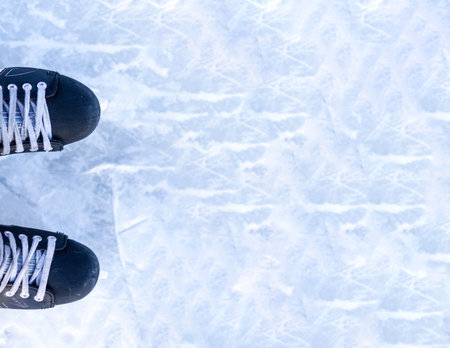 A pair of hockey skates with laces on frozen ice rink closeup. Ice skating or playing hockey in...