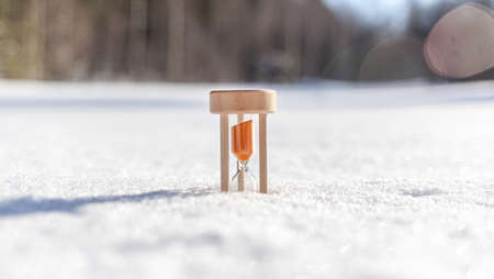 Winter is coming. Hourglass in the snow. sandglass Hourglass as a symbol of the changing of the seasons. Spring is coming. melting snowの写真素材