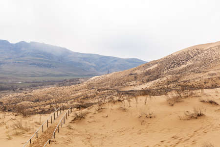 Sarykum dune. Dagestan, Russia. A unique sandy mountain in the Caucasus on a cloudy day. Grass grows on a sand dune.の写真素材