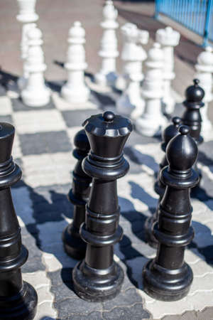 Outdoor chess board with big plastic pieces. Giant size chess in public area zone. Close up big pieces and giant chess board of street chess in the parkの写真素材