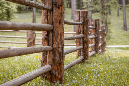 Large wooden fence posts that enclose an old wooden house in the forest. How people built houses and fences in the past. Ecological construction and materials.の写真素材