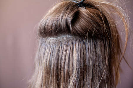 Bundles of hair extensions on a woman's head. Hair extensions to thicken your own. Individual strands of hairの写真素材