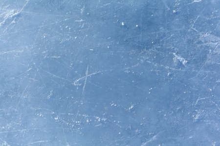 Empty ice rink with skate marks after the session outdoor. skating ice rink texture covered with snow in daylight. Close up of blue ice rink floor, copy spaceの写真素材