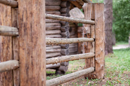 Large wooden fence posts that enclose an old wooden house in the forest. How people built houses and fences in the past. Ecological construction and materials.の写真素材